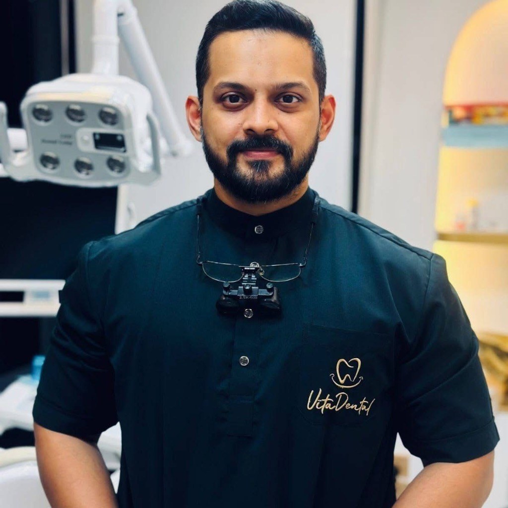 Dr. Arafath in dark scrubs equipped with high-magnification dental loupes